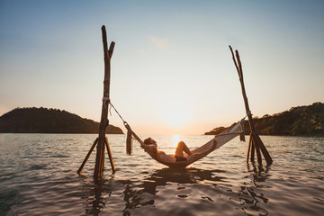 beach getaway, relaxation in hammock at sunset, paradise remote island holidays, happy man tourist...