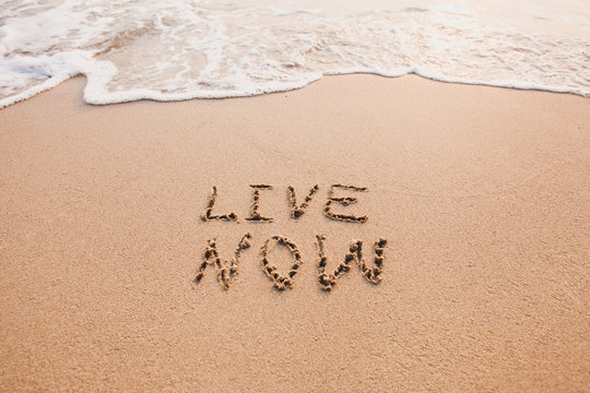 live now, mindfulness concept, text written on the sand