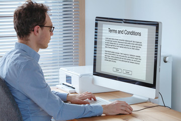 Terms of service, business man reading conditions on the screen of computer.