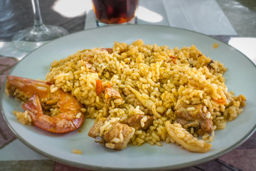 Typical Spanish paella with rice and shrimp on white plate.