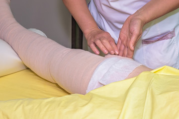 Obraz na płótnie Canvas Lymphedema management: Wrapping leg using multilayer bandages to control Lymphedema. Part of complete decongestive therapy (cdt) and manual lymphatic drainage (MLD)