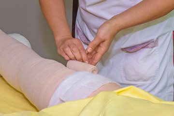Obraz na płótnie Canvas Lymphedema management: Wrapping leg using multilayer bandages to control Lymphedema. Part of complete decongestive therapy (cdt) and manual lymphatic drainage (MLD)