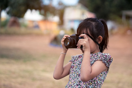 Asian little child girl holding film camera and taking photo