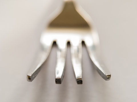 In cutlery or kitchenware, a fork is a utensil, now usually made of metal. Fork head that branches into several narrow and often slightly curved tines on white background. - Image