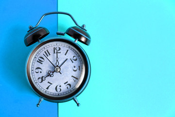 Old, vintage retro alarm clock on a bright blue background.