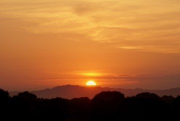 sunset behind the mountains with orange sky