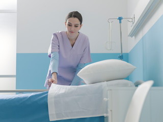 Expert young nurse making the bed at the hospital