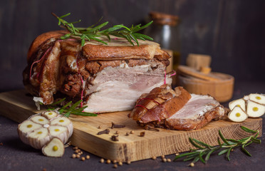 Baked pork brisket with twine on a wooden board. with sliced ​​brisket with rosemary and spices and garlic on a dark background horizontal arrangement