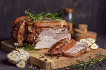 Baked pork brisket with twine on a wooden board.&nbsp;with sliced ​​brisket with rosemary and spices and garlic on a dark background horizontal arrangement