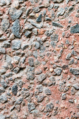 Red concrete wall facing by small black rocks. Texture pattern.