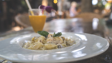 Yummy pasta on cafe table. Closeup plate with portion of tasty pasta with cream sauce placed on table in restaurant