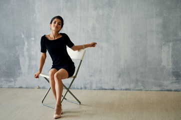young woman in black dress sitting on a chair