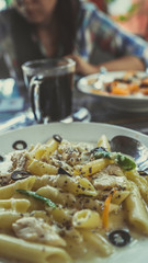 Yummy pasta on cafe table. Closeup plate with portion of tasty pasta with cream sauce placed on table in restaurant