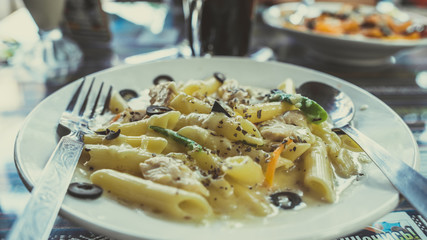 Yummy pasta on cafe table. Closeup plate with portion of tasty pasta with cream sauce placed on table in restaurant