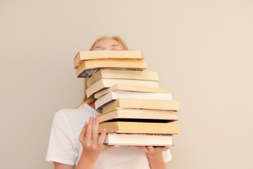 Teenage girl hiding behind big pile of books she wants to read. Student ready to study concept