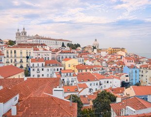 Fototapeta na wymiar Lisbon panoramic view. walls of the buildings of Lisbon, with orange roofs and the Church of Sao Vicente of Fora in the background. Sunny dayand blue sky in summer. Travel and real estate concept. Li