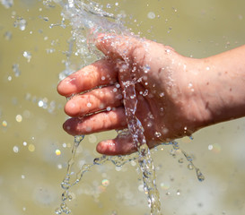 Fototapeta premium Hand of a girl in the spray of water of the fountain