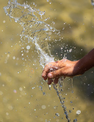 Hand of a girl in the spray of water of the fountain