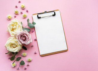 Clipboard and flowers on a pink backgrouns