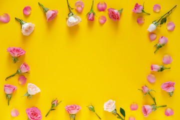 Valentine's Day background. Round frame floral pattern  made of pink and beige roses, green leaves on yellow background. Flat lay, top view.