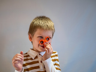 Funny blond child in striped shirt twists spinner on his nose. 4K