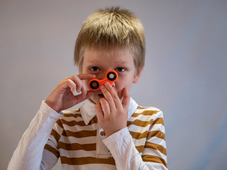 Funny blond child in striped shirt twists spinner on his nose. 4K