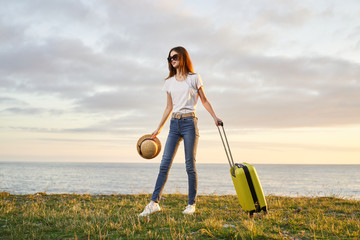 young woman with suitcase on country road