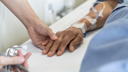 Elderly senior aged patient on bed with geriatric doctor holding hands for trust and nursing health...