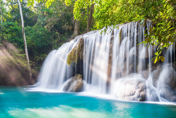 Waterfall and blue emerald water color in Erawan national park with sun light and light ray sunflare, Beautiful nature rock waterfall steps in tropical rainforest at Kanchanaburi province, Thailand