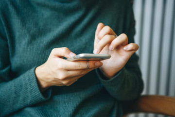 Closeup girl uses a cellphone. Hands with a mobile phone. Modern technology in everyday life.