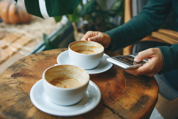 The girl uses a cell phone and drinks coffee. She has a meeting or she drinks a morning cappuccino or flat white.