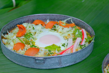 Delicious egg pan with sausage ,crab stick, cabbage and lettuce in small metal pan on green banana leave. Healthy breakfast in morning.
