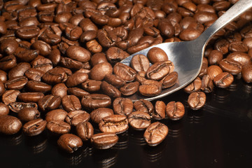 Roasted espresso coffee beans with spoon closeup