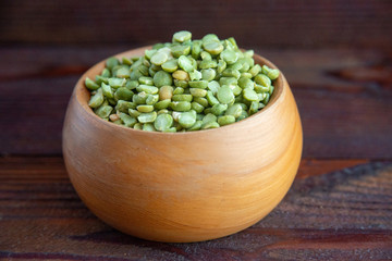 Green dried peas in wooden bowl on table, close-up rustic