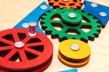 children's toy - wooden gears with sharp teeth, represent a complex mechanism and symbolize teamwork. Multicolored vibrant wooden details