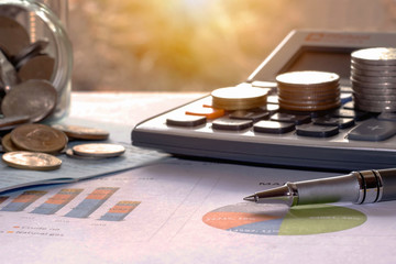 Pens and coins placed on financial reports or stock market graph analysis.