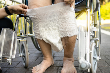 Caring female nurse assisting a elderly patient with giving diaper change,asian senior woman put...