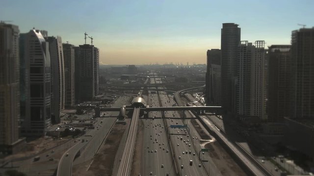 Aerial view of a big urban highway, modern skyscrapers and distant seaport. Dubai, UAE