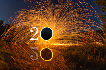 2020 written on the air with flying burning sparks