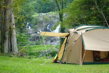 Foto auf Acrylglas Campingzelt am Wasserfall und Bach mit Baum im grünen Dschungel oder Wald für den Sommer-Winterurlaub Entspannung und Urlaubsreise mit Trekking und Picknick auf Wiesengras am Khlong Nam Lai Wasserfall © kornnphoto