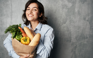 young woman holding shopping bag full of groceries