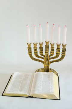 Menorah and open bible with 7 unlit candles isolated on white background. Vertical shot. Copy space.
