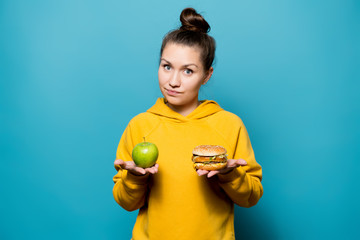 nice girl holds an apple and a burger in her palms