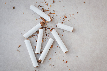 Scattered crushed cigarettes and tobacco on a neutral background. Smoking cessation concept.