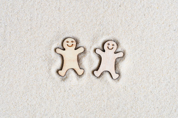 Two funny happy wooden men lie on the sand at the beach. Concept. Flat lay. Aerial view