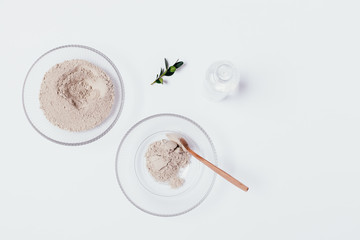 Bowl with dry clay powder next to bottle of water