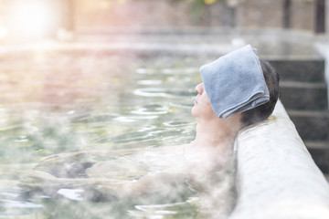 Nature Hotsping ans onsen travel tourism concept. Asia man relax in natural hot spring water pool during vacation.