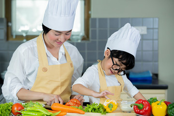 Happy  Asian  mother  with  son  preparing  fresh  vegetables  and  fruit  in  modern kitchen at home