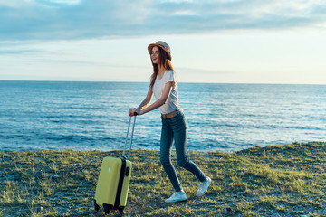 young woman with suitcase on the beach
