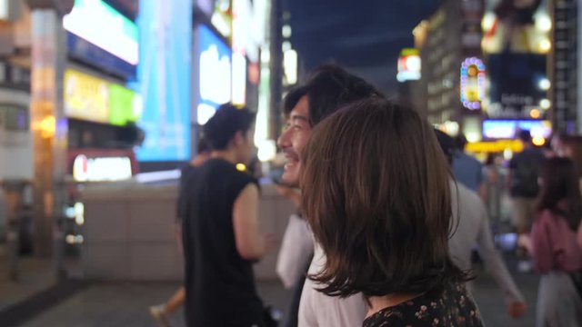 Excited couple walking crazy nightlife Neon streets of Osaka traveling in Asia